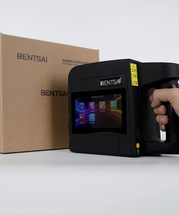 Image of the BENTSAI B45 Handheld Printer, a compact, portable device with a rectangular body and ergonomic handle. The printer features a digital display on the top for easy control, along with buttons for settings and operation. It has a built-in cartridge slot for quick ink replacement and is designed for printing on a variety of surfaces, including paper, wood, plastic, and metal. The sleek, black and gray design emphasizes its modern, industrial functionality.